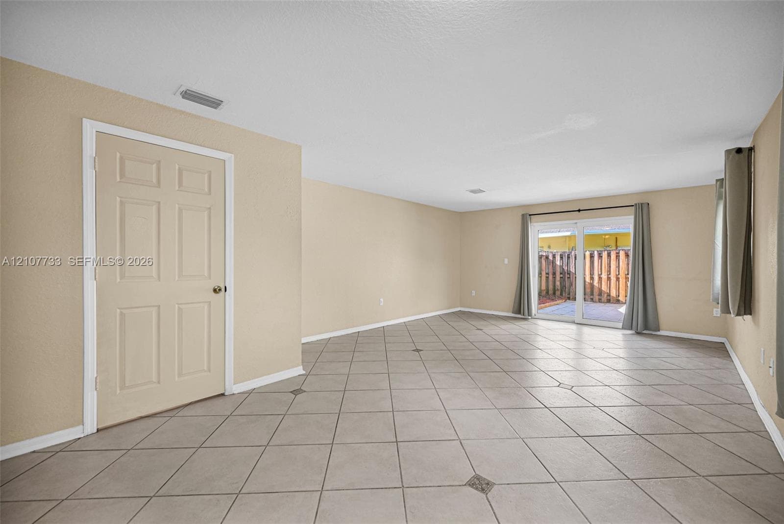 Interior space featuring large-format ceramic tile flooring with decorative stone accents, neutral-toned walls, and sliding glass doors with direct exterior access