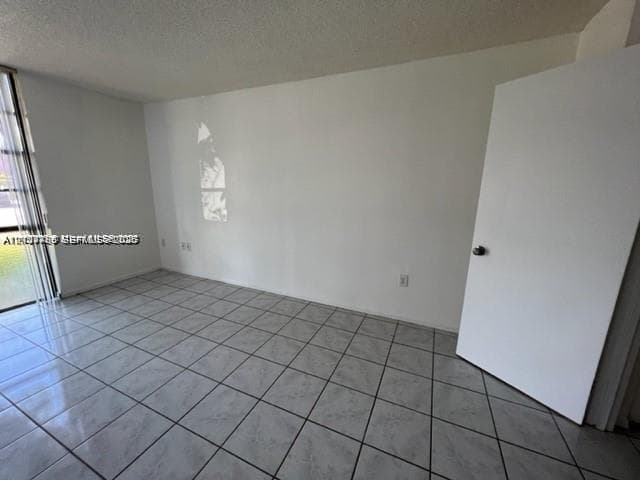 Room featuring large-format ceramic tile flooring and floor-to-ceiling glass sliding doors