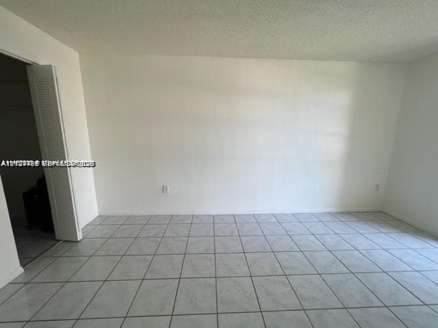 Neutral interior space featuring large-format ceramic tile flooring and a bi-fold closet door