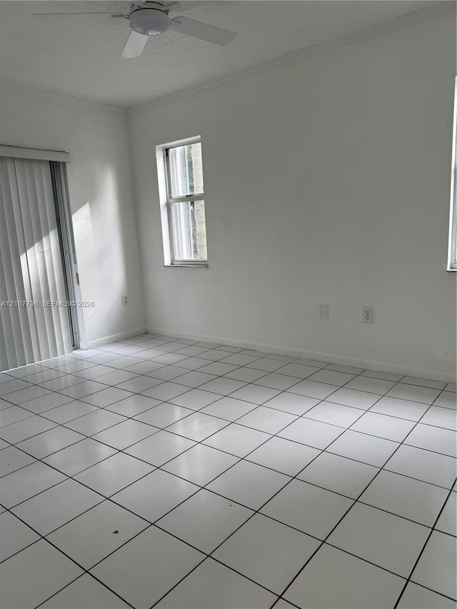 Interior space featuring white tile flooring, vertical window blinds, and a ceiling fan
