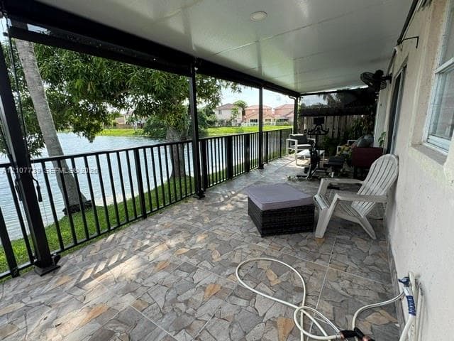Covered patio featuring stone-tile flooring, metal perimeter railing, recessed ceiling lighting, and waterfront positioning