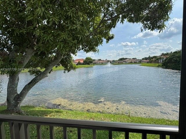 Waterfront property featuring a lake, water fountain, and mature tree