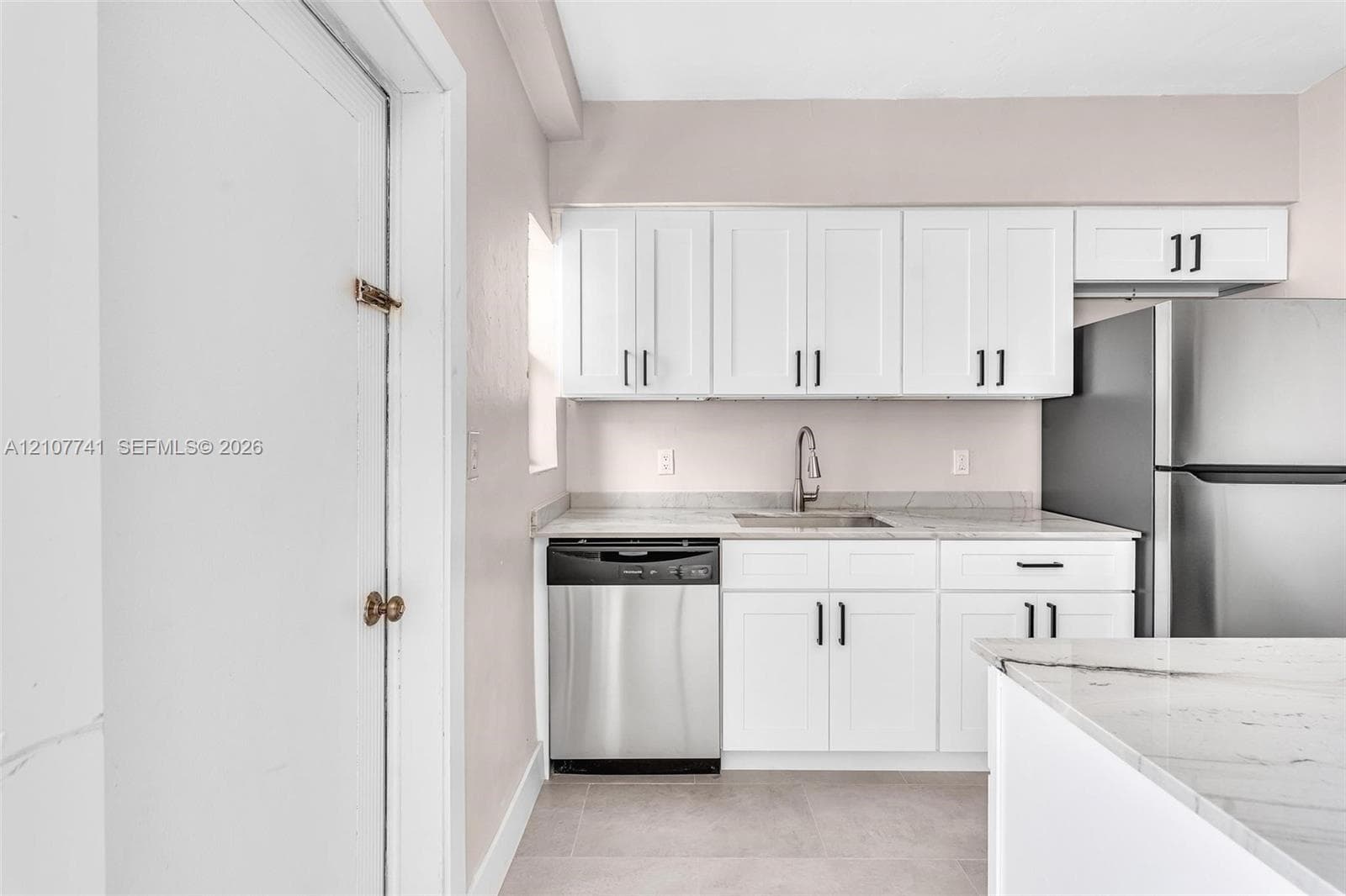 Neutral-toned interior space featuring light-colored tile flooring, a built-in closet with overhead shelving, and a ceiling-mounted light fixture with a multi-blade fan