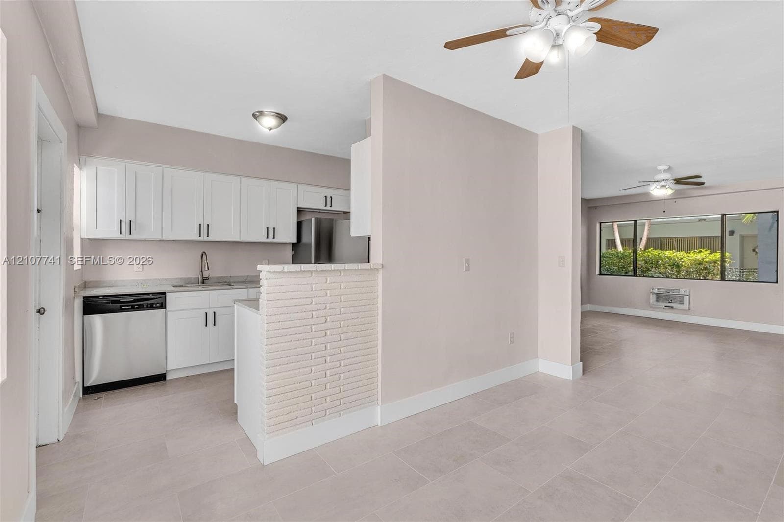 Interior room featuring large format tile flooring, a multi-blade ceiling fan with integrated lighting, and a horizontal window with a black frame