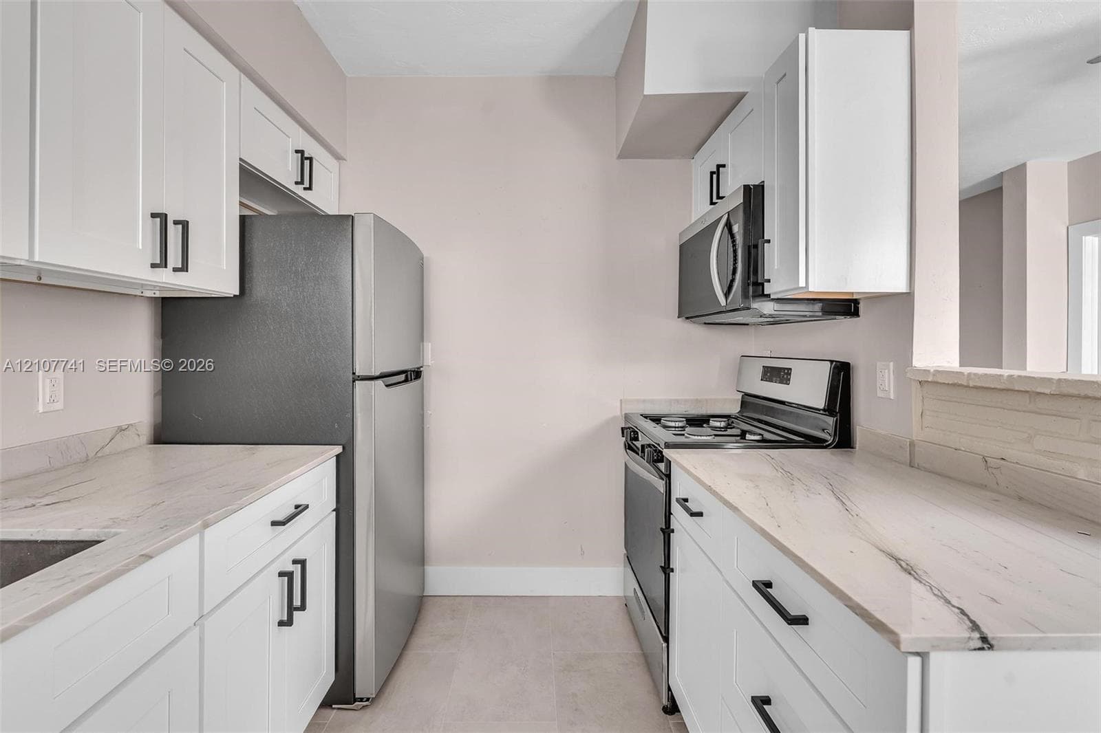 Bathroom featuring large-format ceramic wall tiling, a white vanity with integrated basin, polished chrome plumbing fixtures, and neutral floor tiling