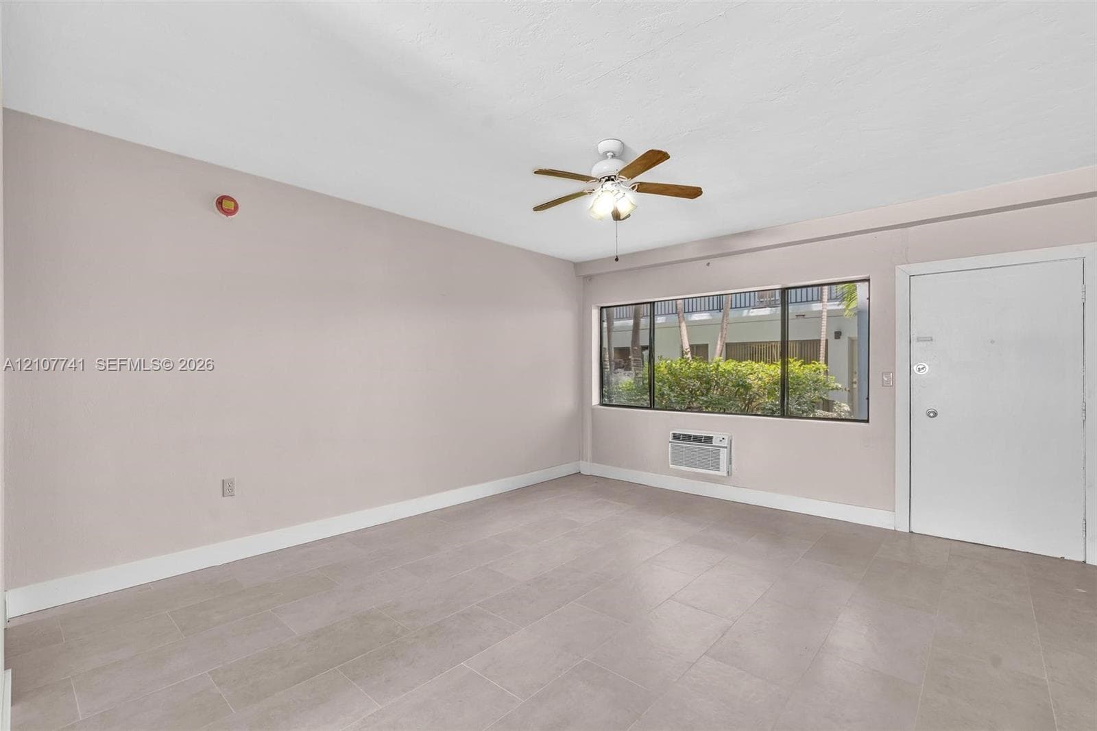 Interior space featuring neutral wall paint, large-format tile flooring, dual ceiling fans, and a brick-texture wall detail