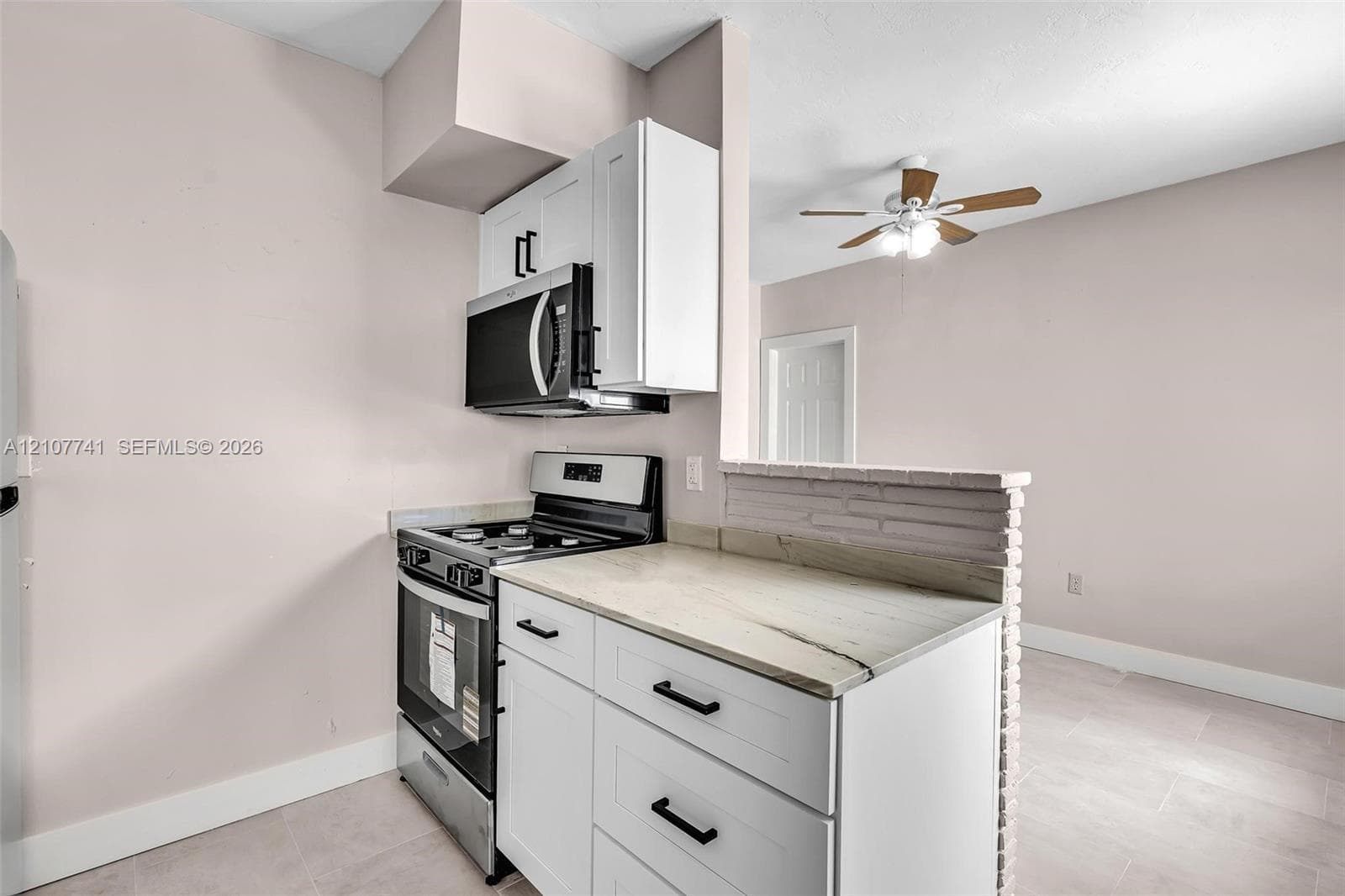 Outdoor laundry area featuring stacked and side-by-side white washer and dryer units, concrete flooring, and metal protective awning under a covered exterior structure