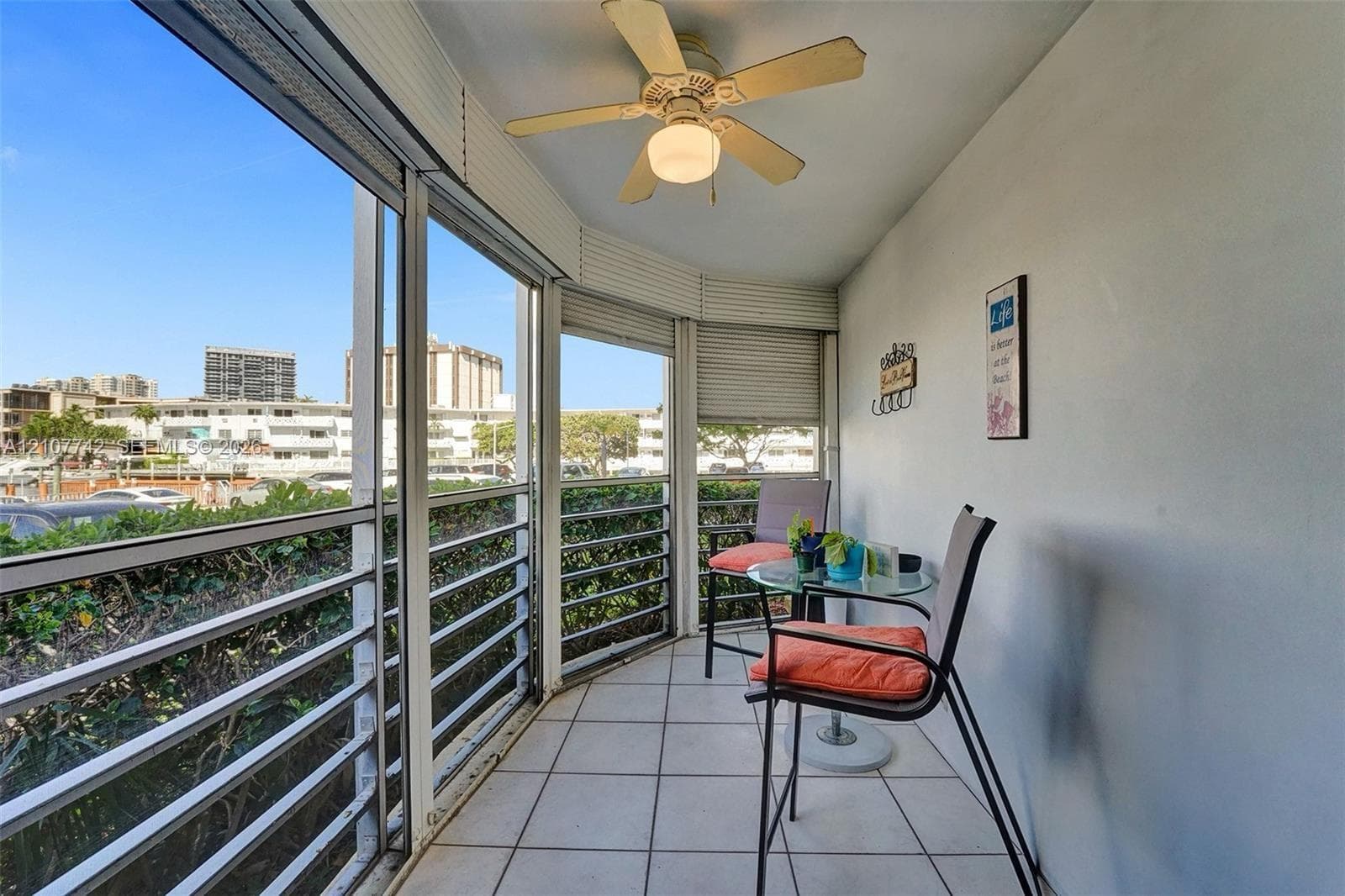 Enclosed balcony featuring tile flooring, ceiling fan, and floor-to-ceiling windows with horizontal blinds