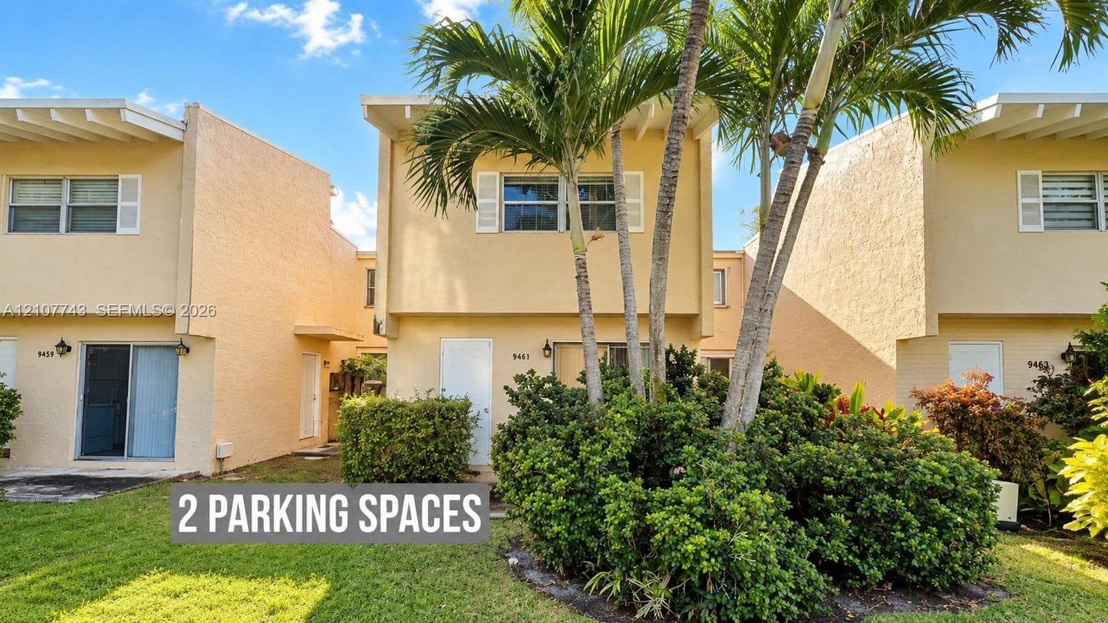 Multi-level exterior featuring stucco siding, exposed rafter tails, louvered shutters, and mature palm landscaping