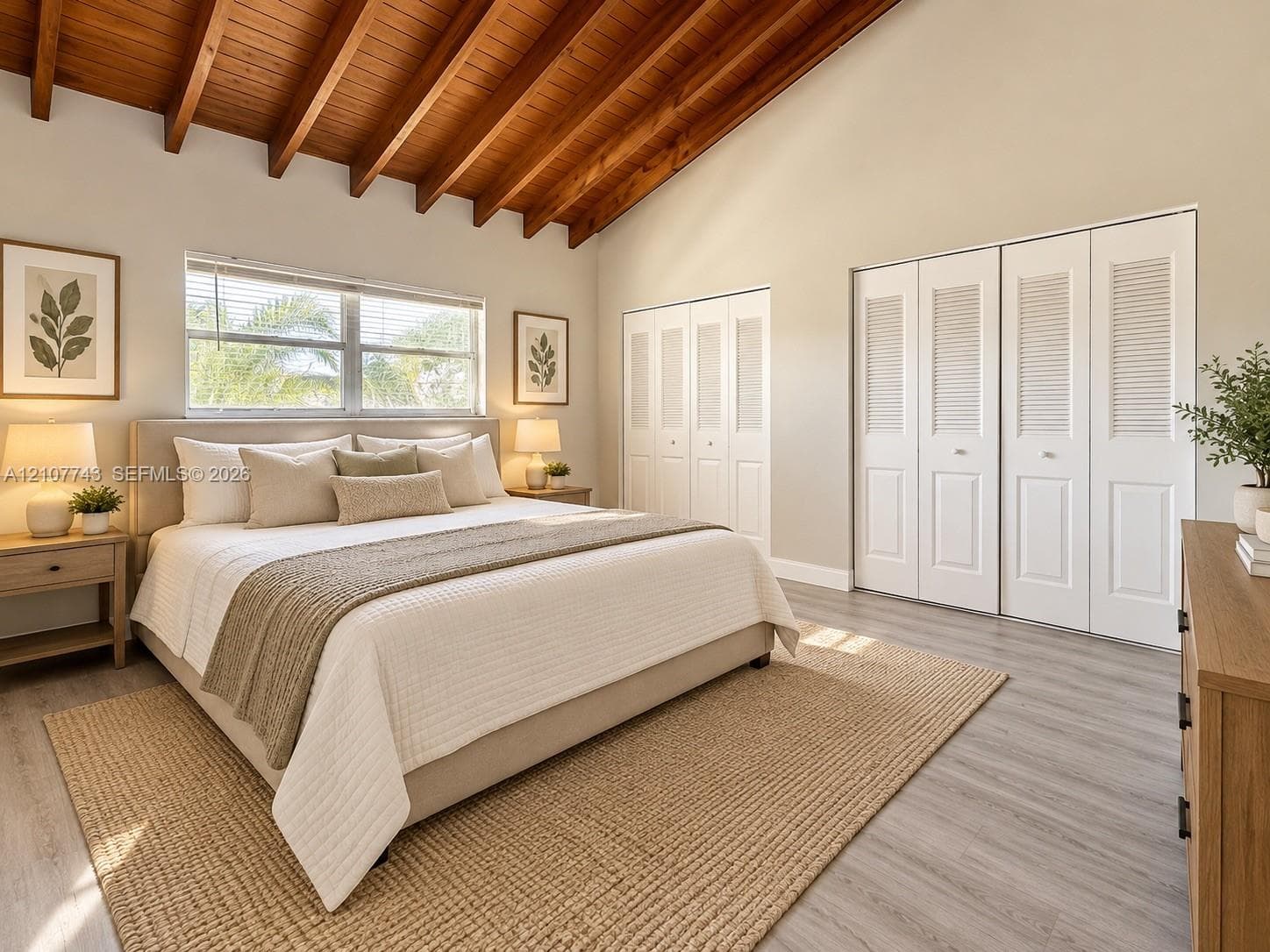 Vaulted ceiling with exposed wood-finish beams, white louvered-style closet doors, and wood-finish flooring