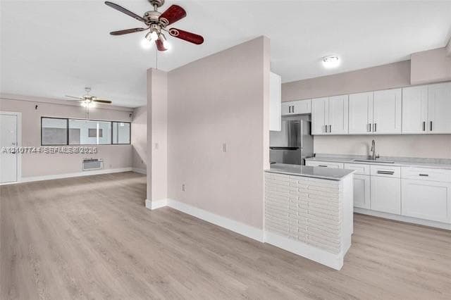 Kitchen featuring white cabinetry, stone-finish countertops, and a white brick-accented peninsula, complemented by wood-finish flooring and dual ceiling fans