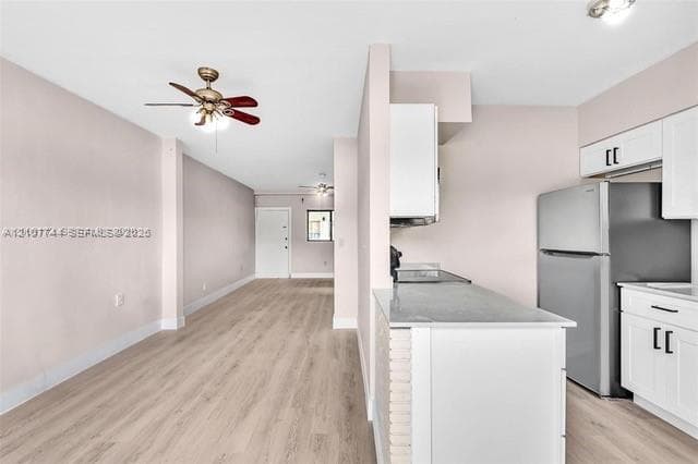 Kitchen featuring white cabinetry, stone-surface countertops, and stainless steel refrigerator