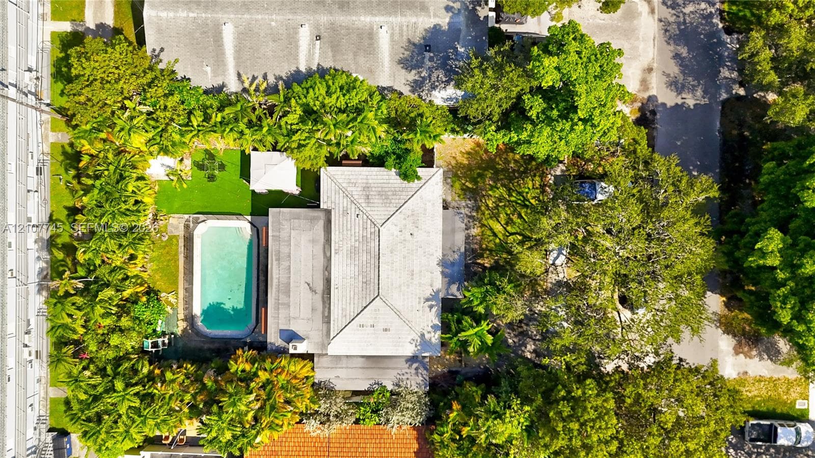 Aerial perspective of property featuring an inground swimming pool, manicured lawn, paved patio area, and mature perimeter landscaping