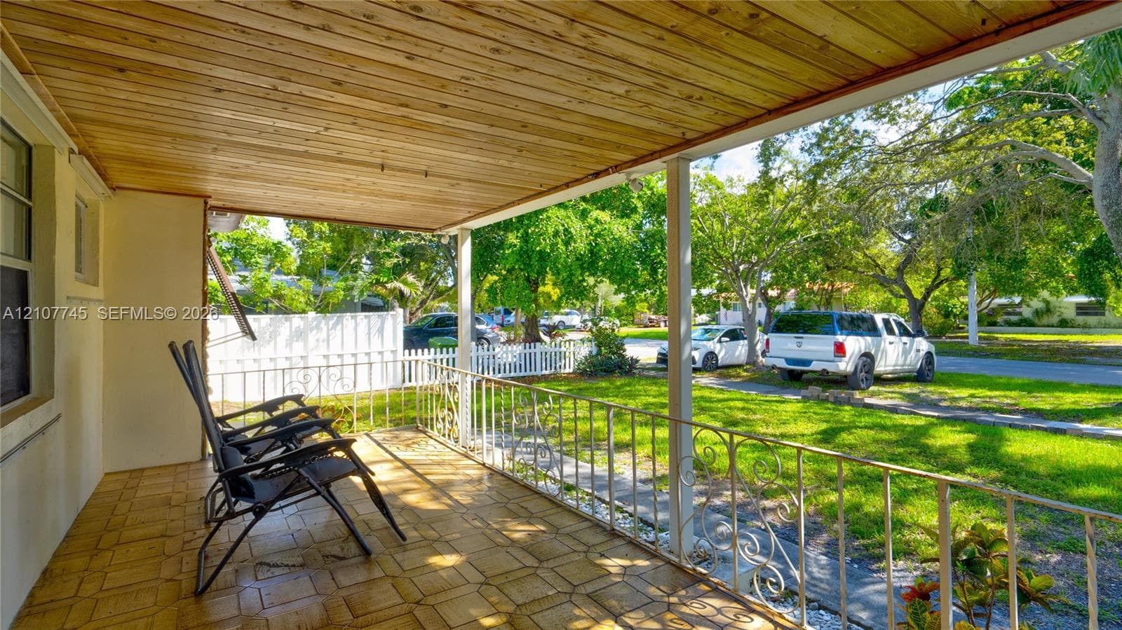 Covered porch featuring a wood-plank ceiling, tiled flooring, and decorative metal railings