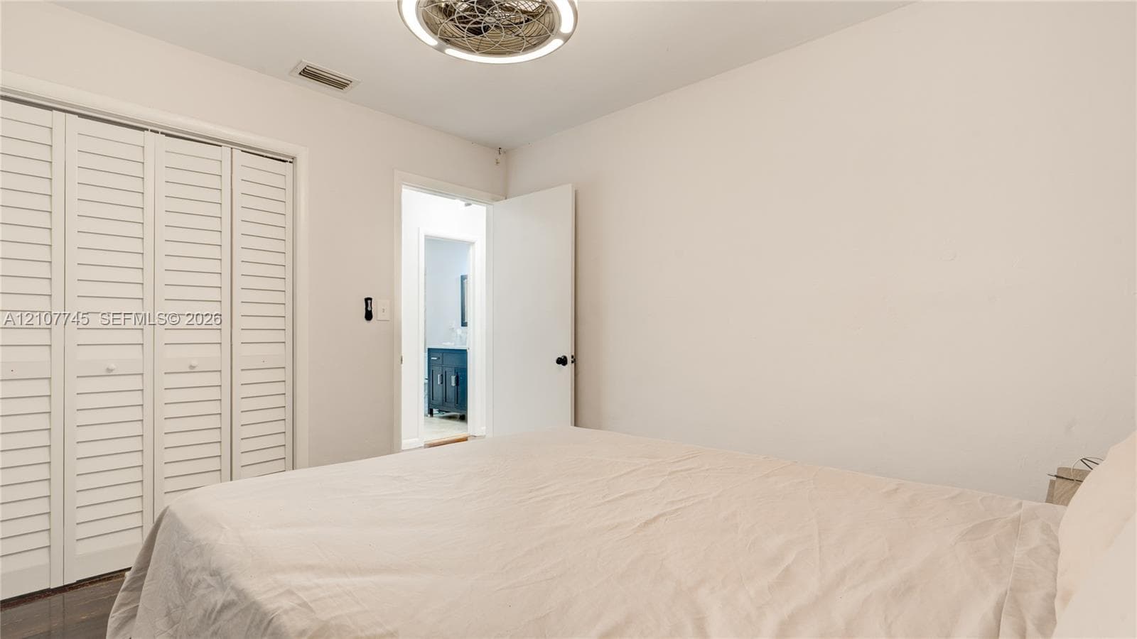 Room featuring louvered bi-fold closet doors, a circular ceiling-mounted light fixture, and a solid-core interior door