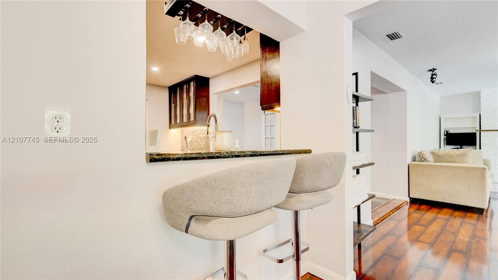 Pass-through window featuring a stone-finish countertop, dark wood-finish cabinetry, built-in stemware rack, and wood-finish flooring