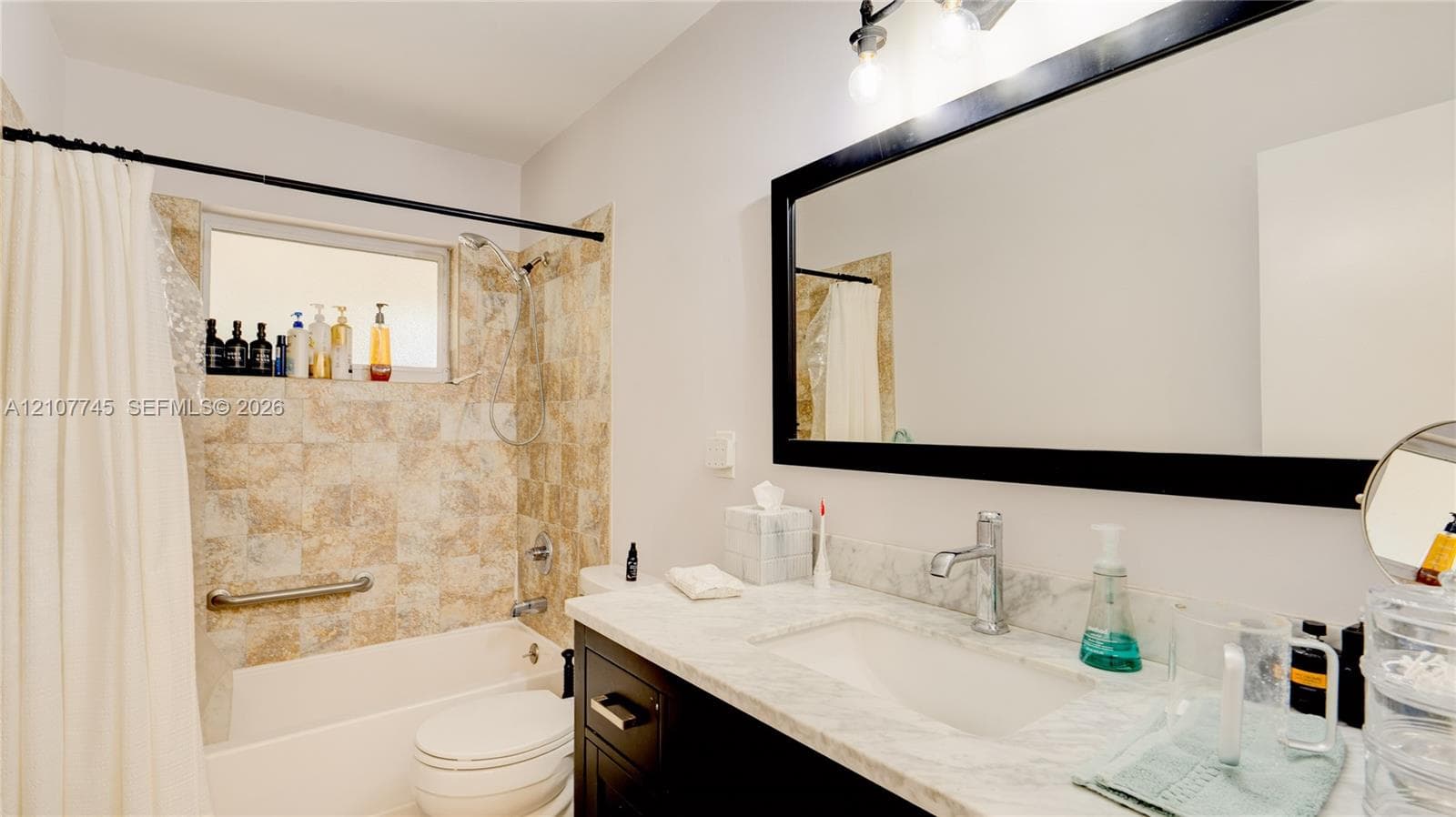 Bathroom featuring a vanity with a light-toned stone countertop, integrated sink, and dark cabinetry