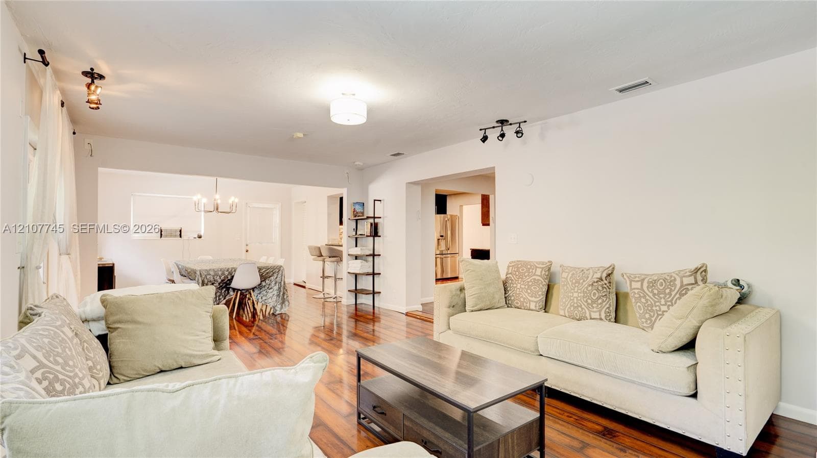 Open floor plan featuring wood-finish flooring, multi-directional ceiling-mounted lighting, and neutral wall tones