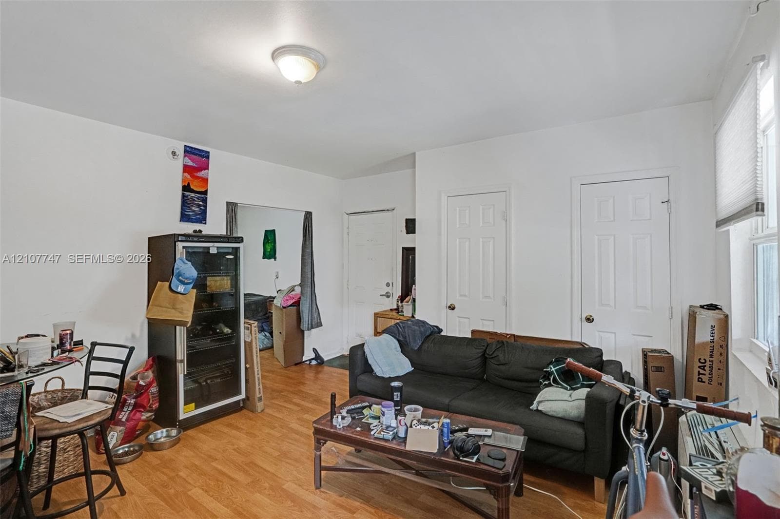Wood-finish flooring, two six-panel interior doors, and a window with a cellular shade