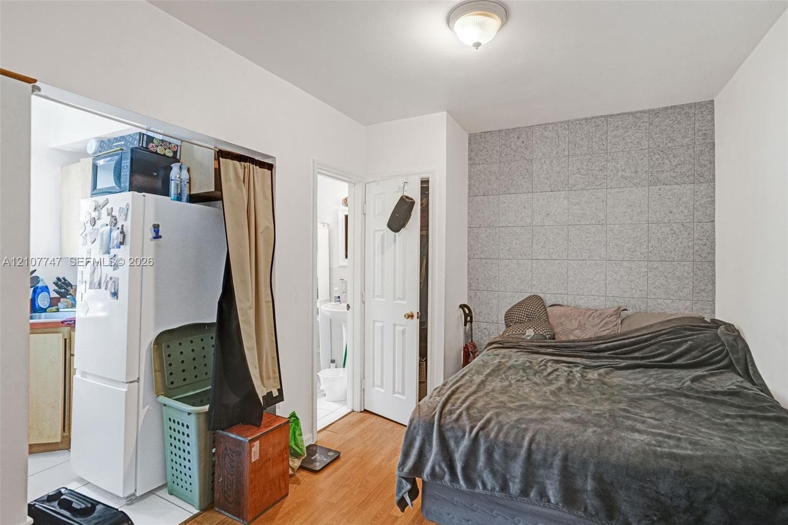 Wood-finish flooring, stone-tiled accent wall, and flush-mount overhead lighting