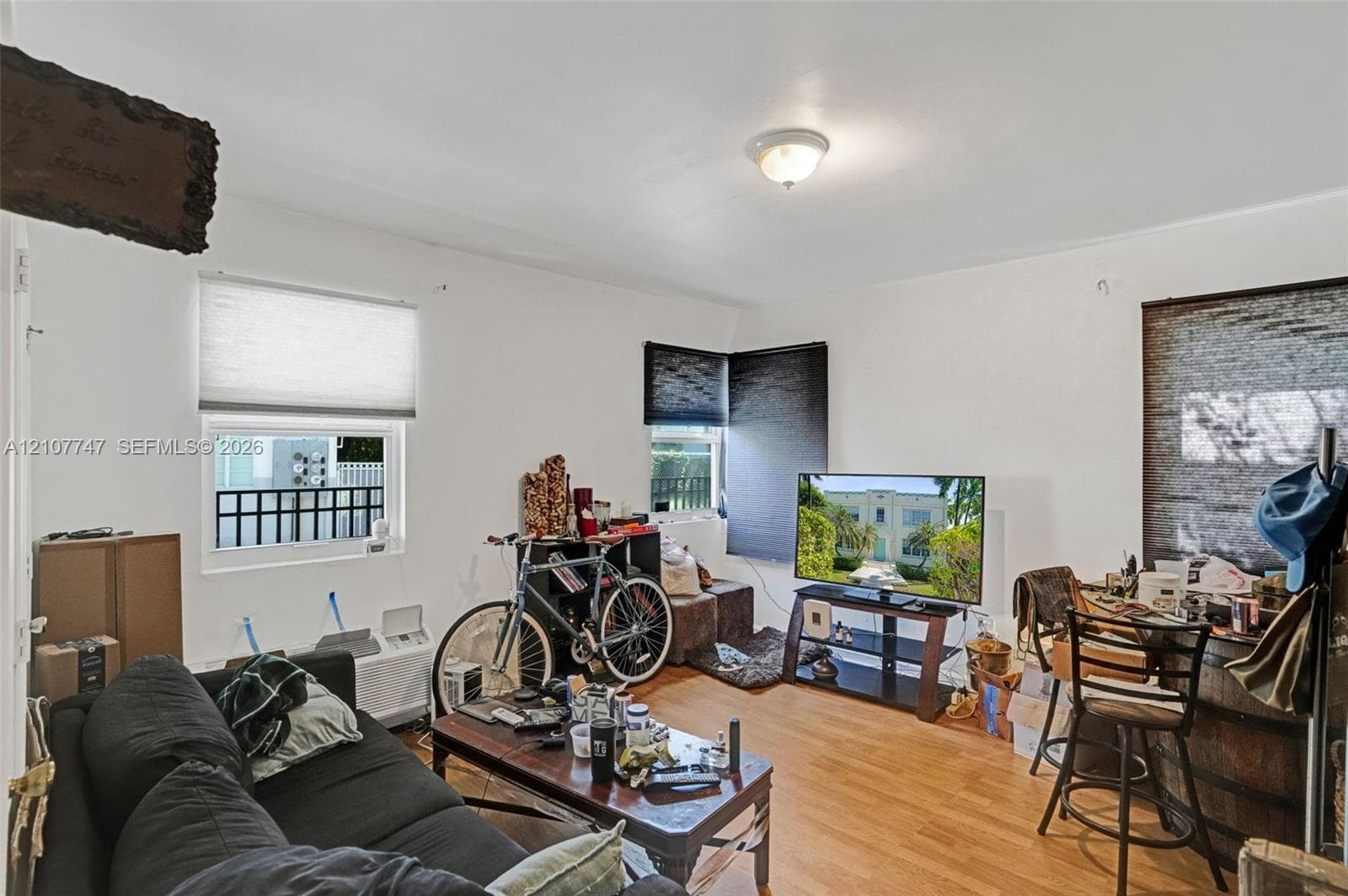 Room featuring wood-finish flooring, multiple windows, and a flush-mount ceiling light