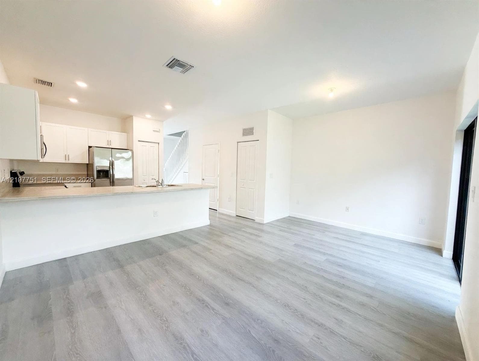 Kitchen featuring white cabinetry, wood-finish flooring, a breakfast bar, stainless steel appliances, and recessed lighting