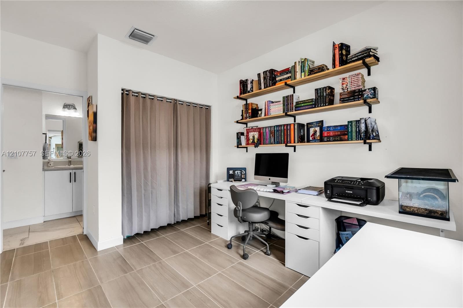 Room featuring large-format ceramic tile flooring, built-in wall-mounted shelving, and a double-door closet