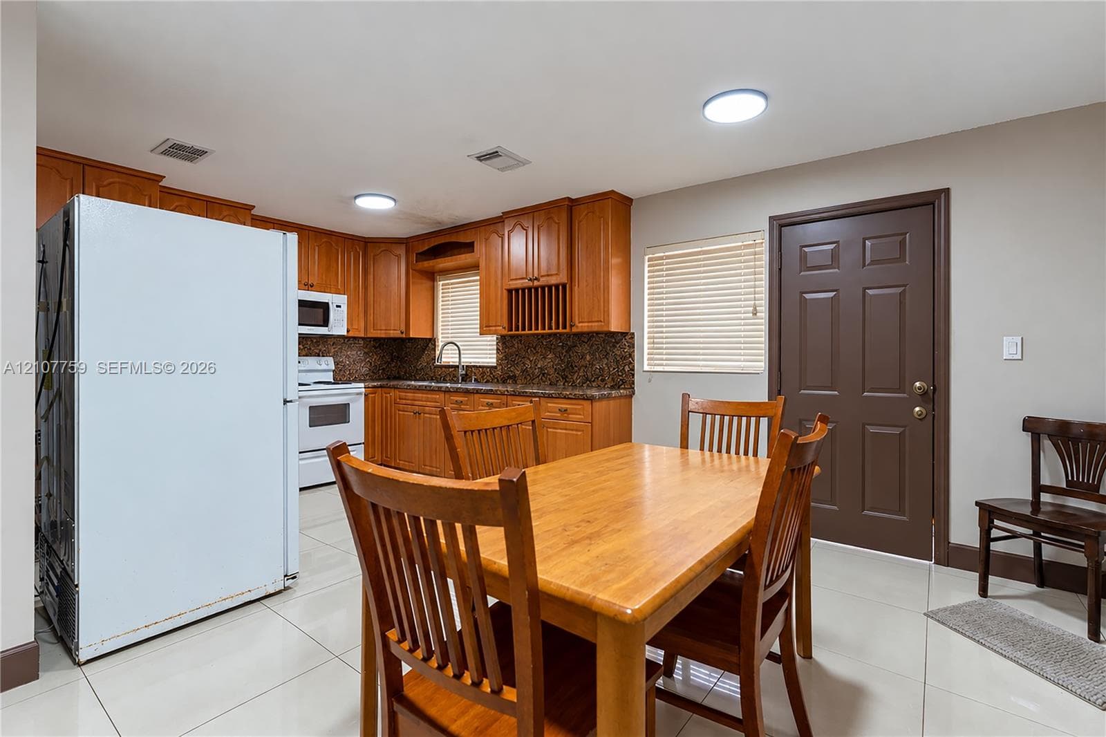 Kitchen featuring wood cabinetry, stone countertops, tiled flooring, and built-in appliances
