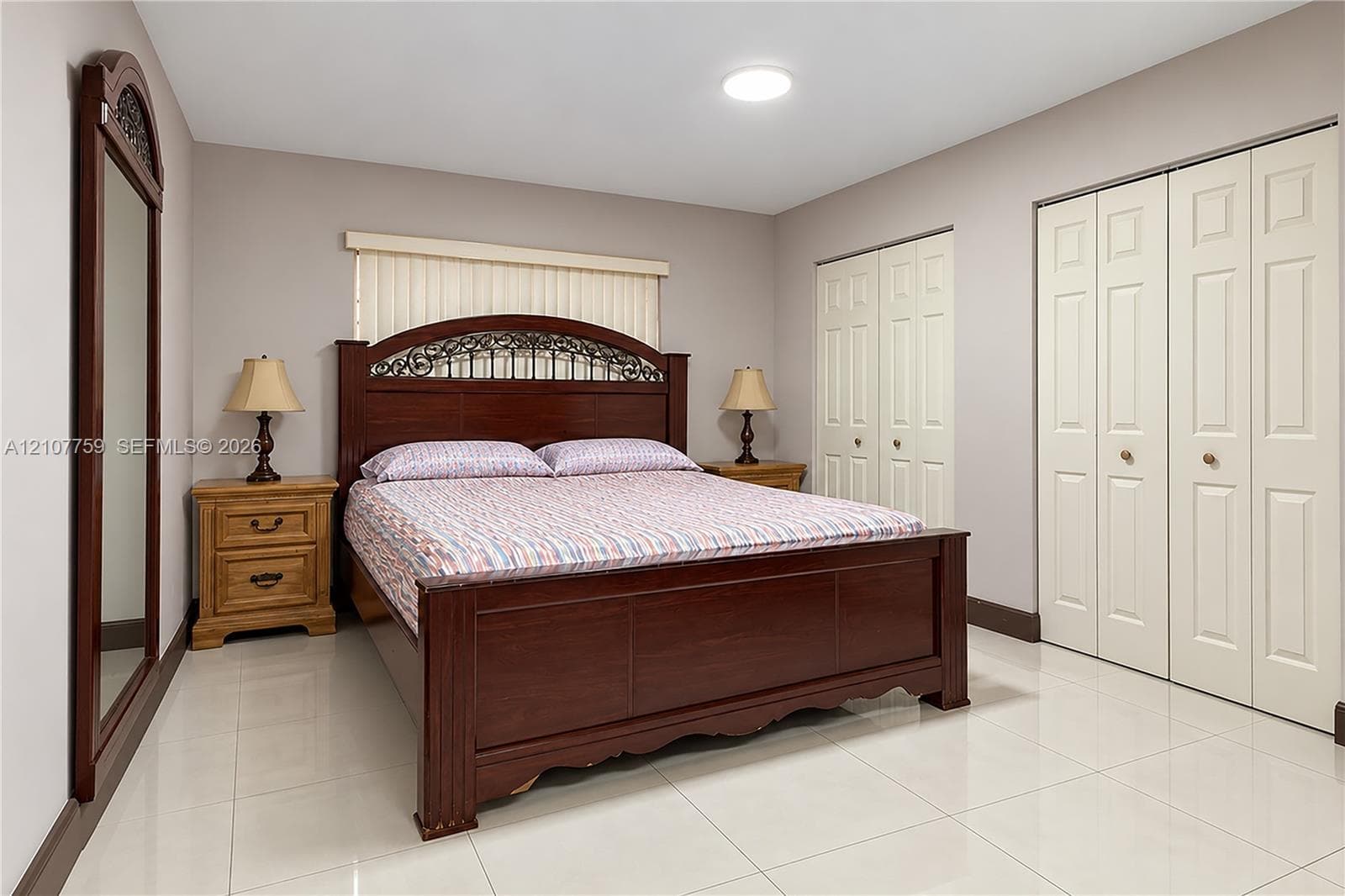 Neutral interior with light-colored tile flooring, flush-mount ceiling lighting, and dual sets of bi-fold closet doors