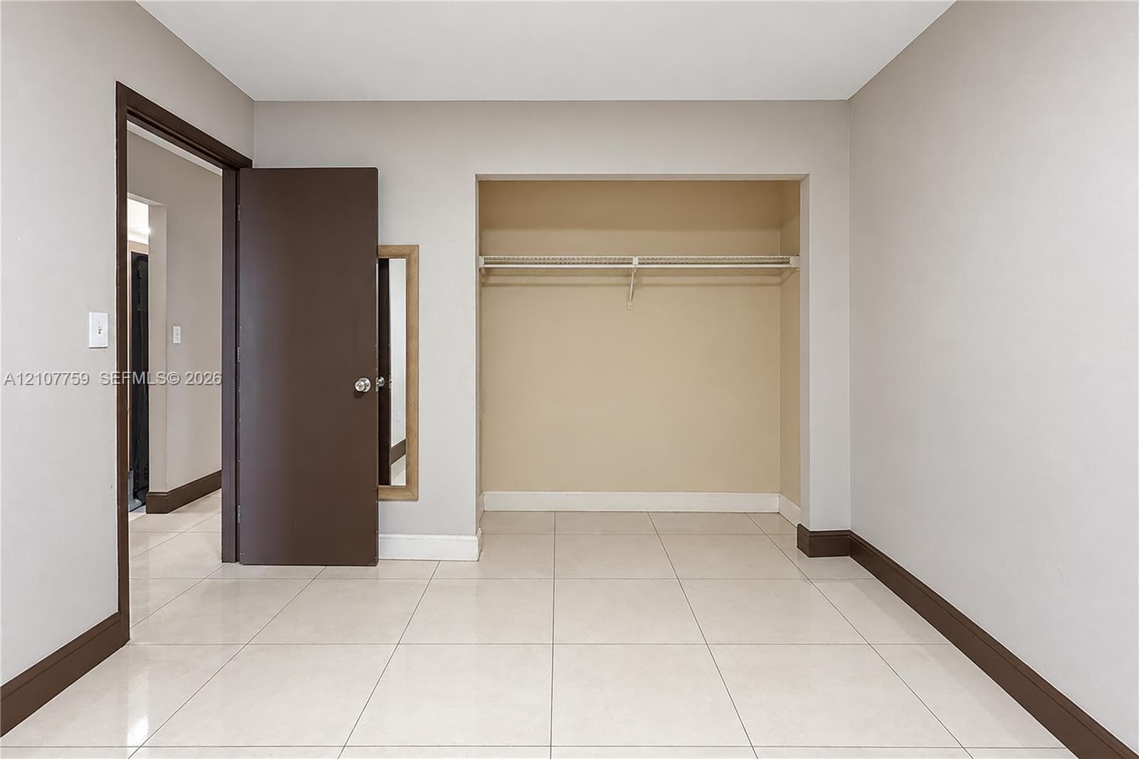 Room interior featuring large-format tile flooring, a built-in closet with wire shelving, and dark-finish door casing
