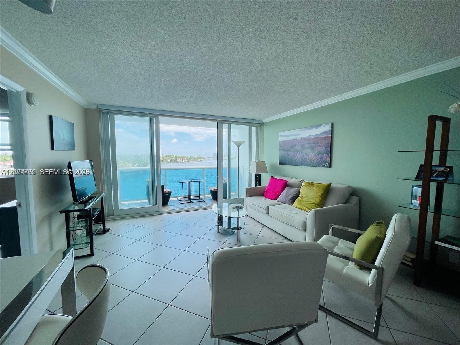Living area featuring expansive floor-to-ceiling glass sliding doors, ceramic tile flooring, and access to a balcony with a glass railing