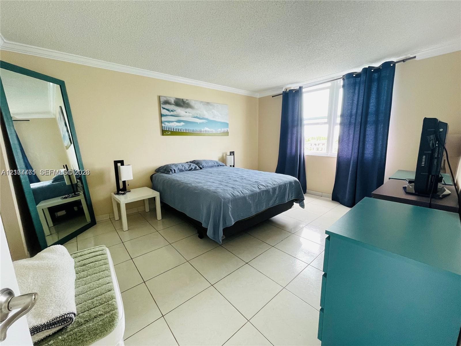 Bedroom featuring large format light-toned tile flooring, crown molding, and expansive windows