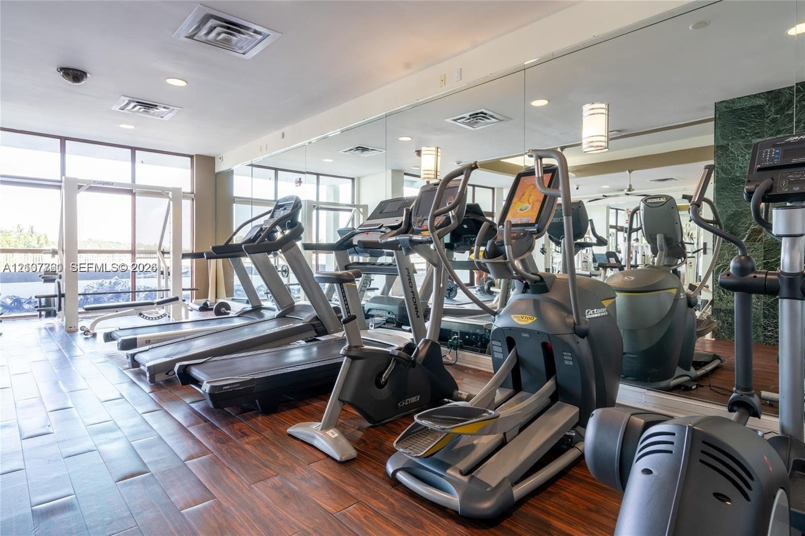Fitness center featuring wood-finish flooring, floor-to-ceiling mirrors, recessed lighting, and expansive windows