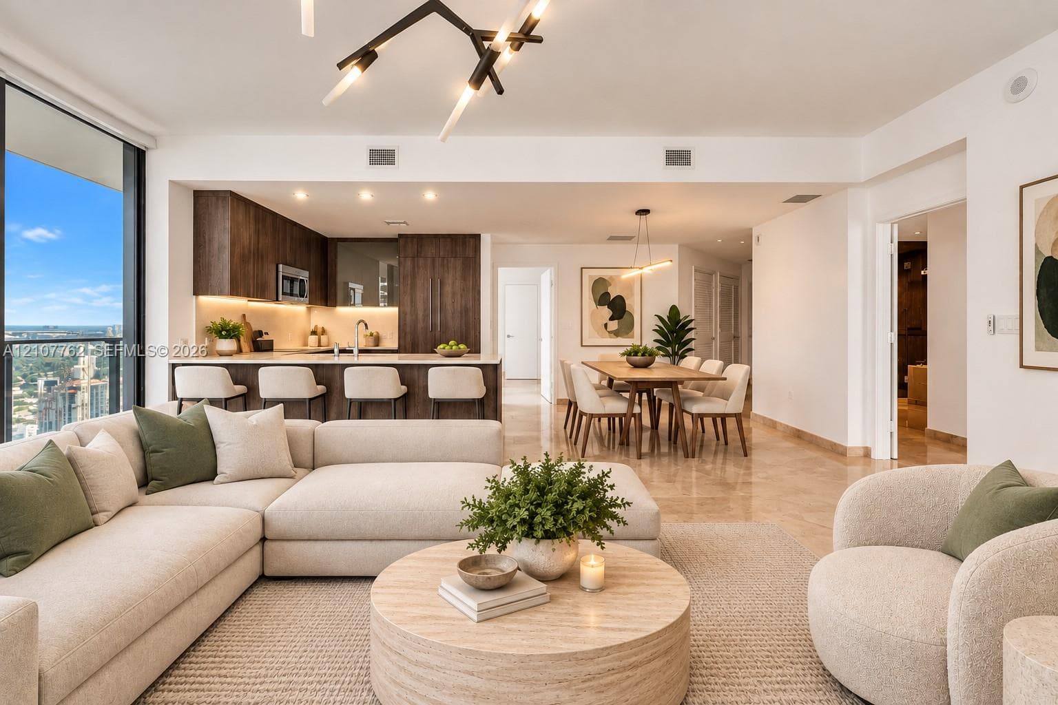 Open-concept interior featuring floor-to-ceiling windows, dark wood cabinetry, an integrated kitchen peninsula, recessed lighting, and modern geometric chandelier