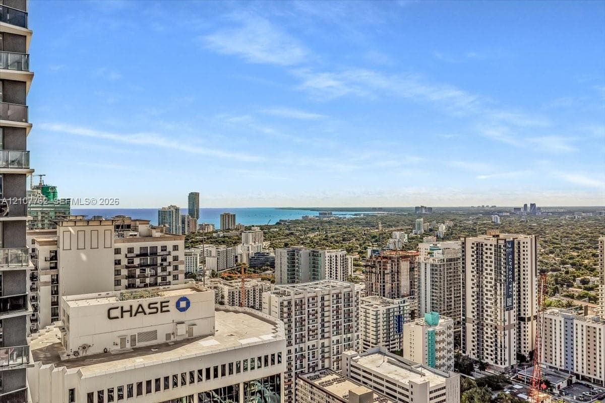 High-rise residential balcony featuring glass panel railings and expansive urban and coastal horizon scenery