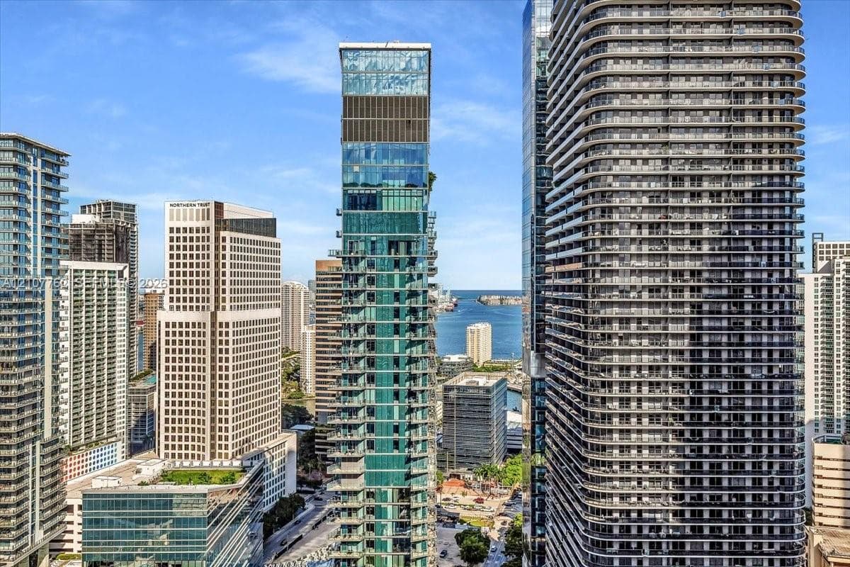 High-rise urban towers featuring glass facades, expansive window arrays, and balcony tiers, set within a metropolitan skyline near a harbor