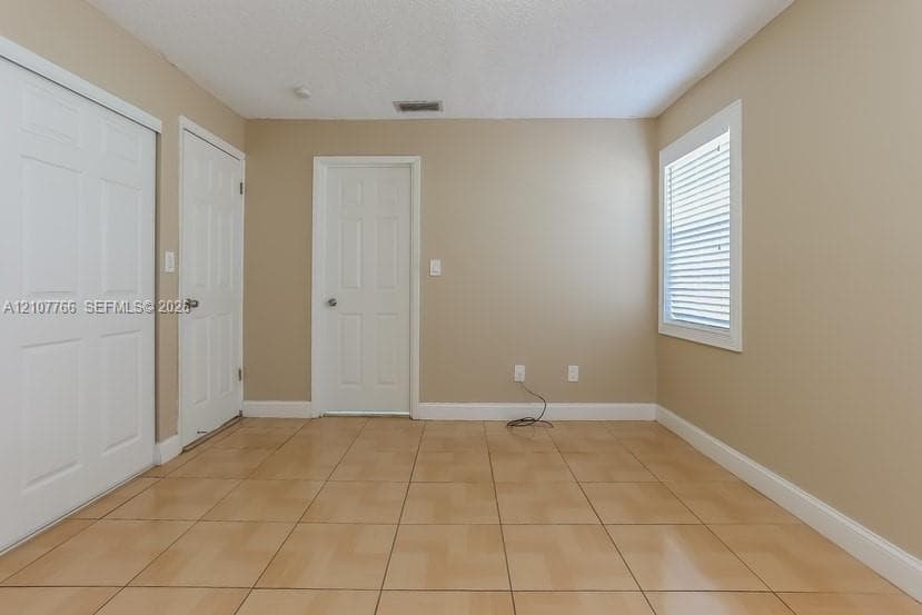 Room featuring neutral wall paint, tile flooring, and a sliding-door closet