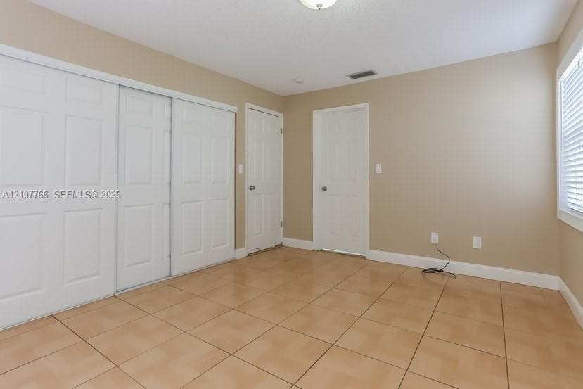 Ceramic tile flooring, sliding closet doors with raised panels, and interior doors with matching trim