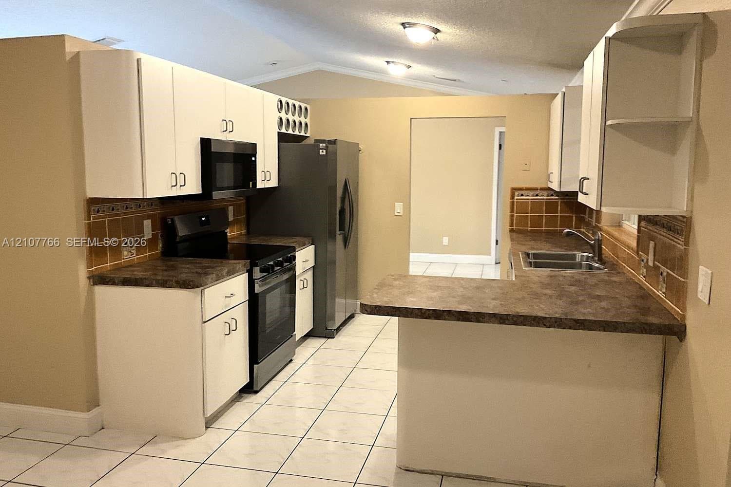 Kitchen featuring white cabinetry, solid surface countertops, tiled backsplash, integrated wine storage, and ceramic tile flooring