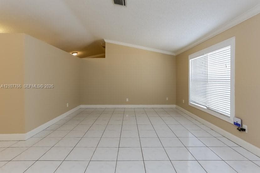 Interior space featuring vaulted ceilings, neutral wall tones, white ceramic tile flooring, and a window with horizontal blinds