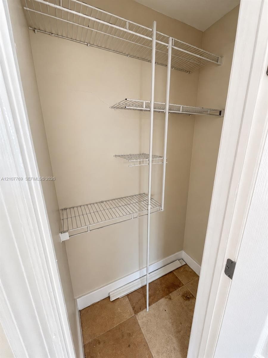 Storage area featuring white wire shelving units and tiled flooring