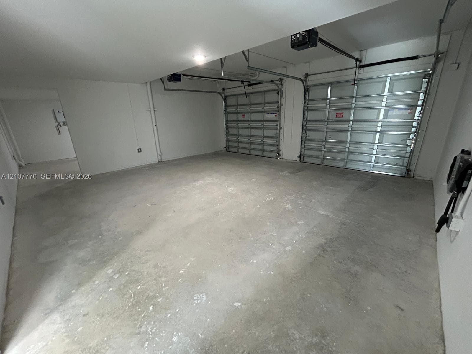 Two-car garage featuring a concrete floor, high ceilings, and dual motorized garage door openers