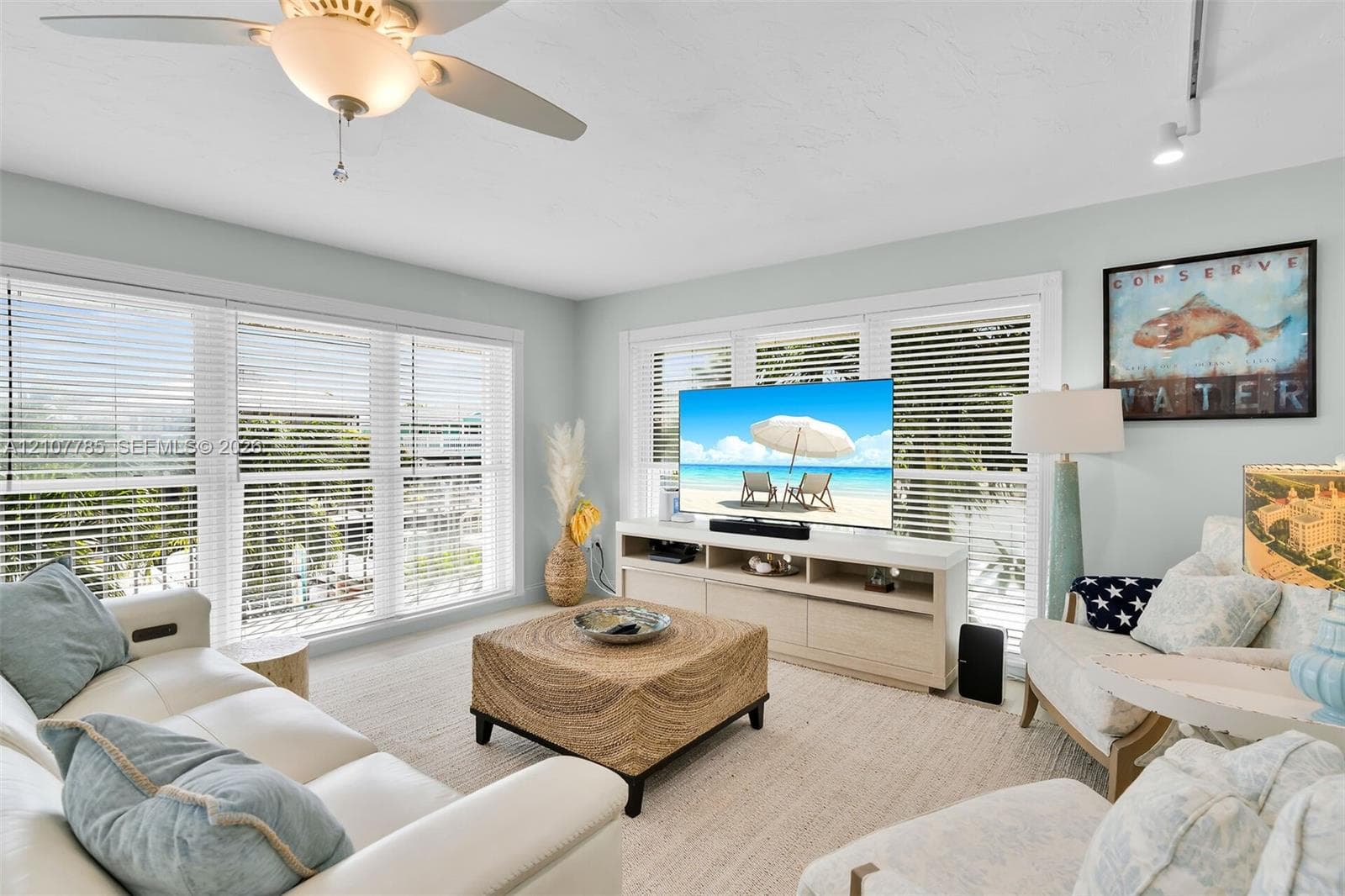 Living area featuring multi-panel windows with adjustable horizontal blinds, ceiling-mounted fan with integrated lighting, and track lighting fixtures