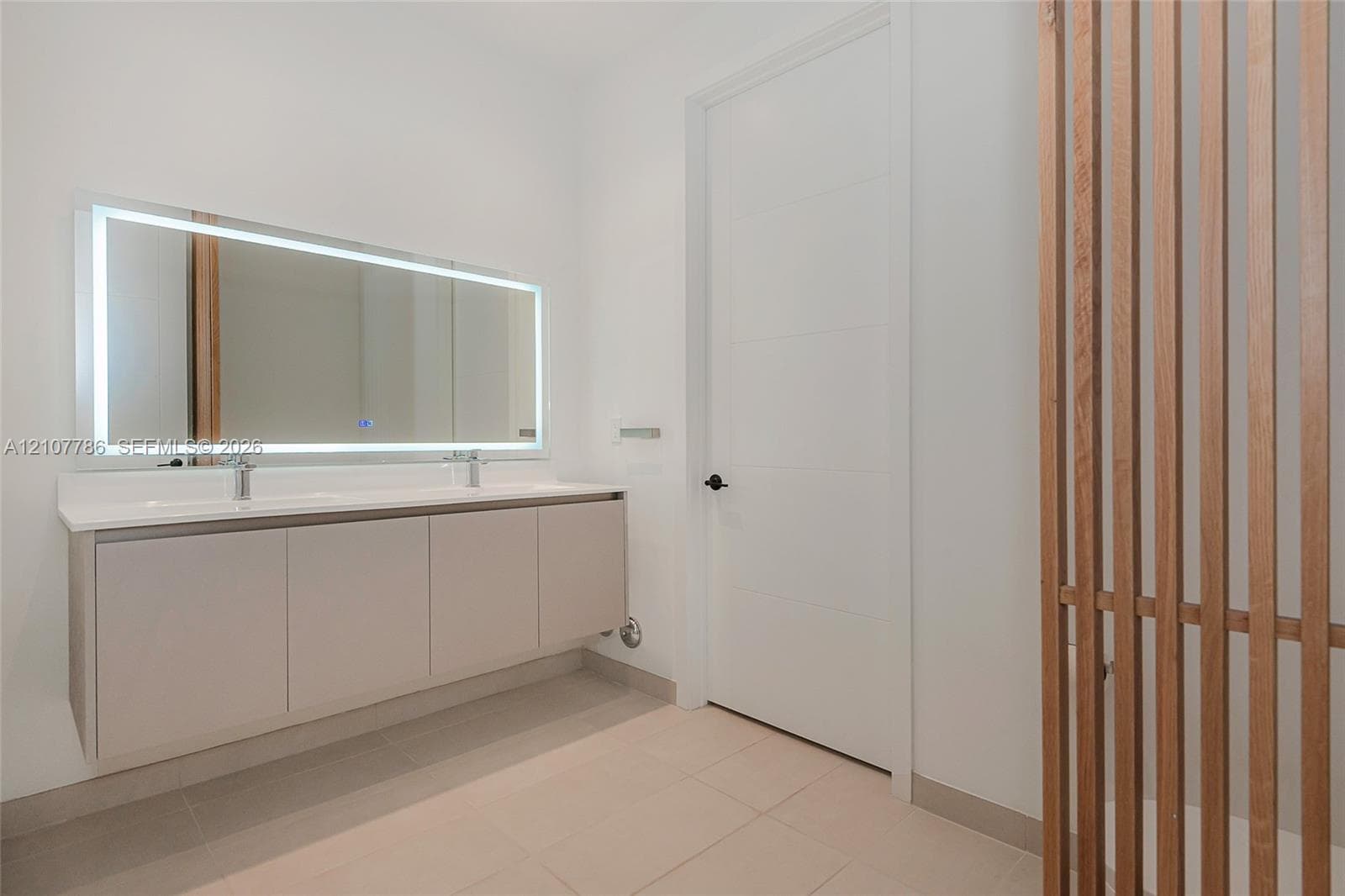 Floating dual-sink vanity with a solid-surface countertop, rectangular LED-backlit mirror, and decorative vertical wood slat screen