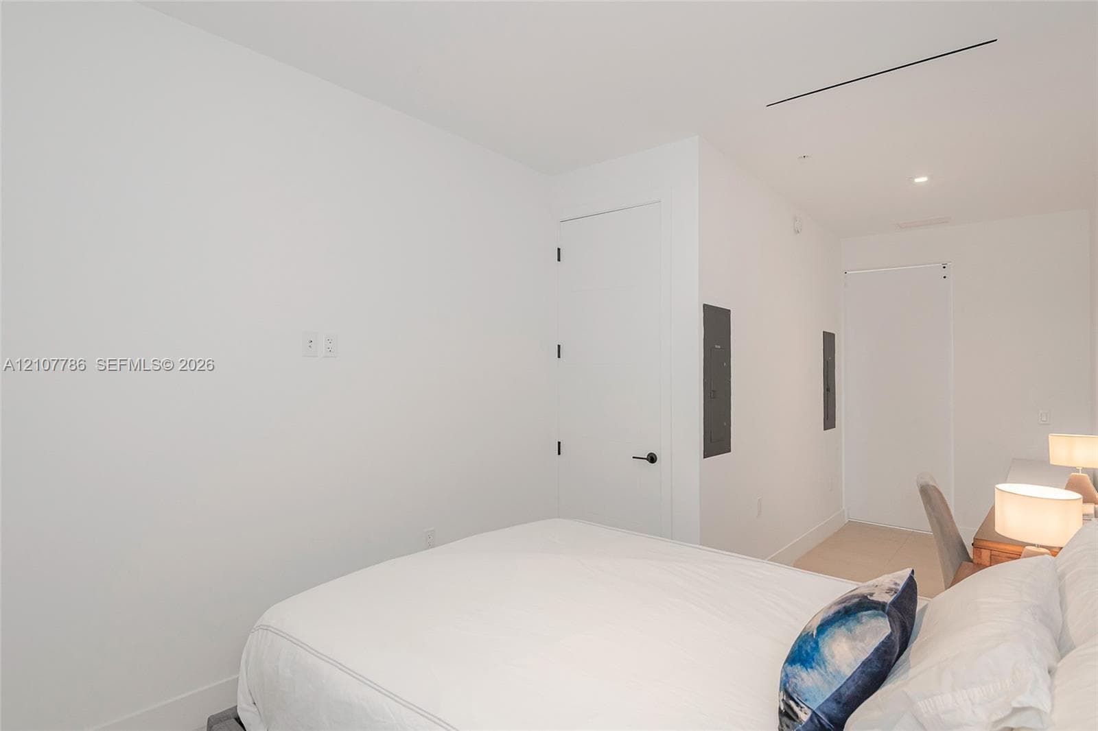 Minimalist interior featuring smooth walls, recessed ceiling lighting, and solid core doors with matte black hardware