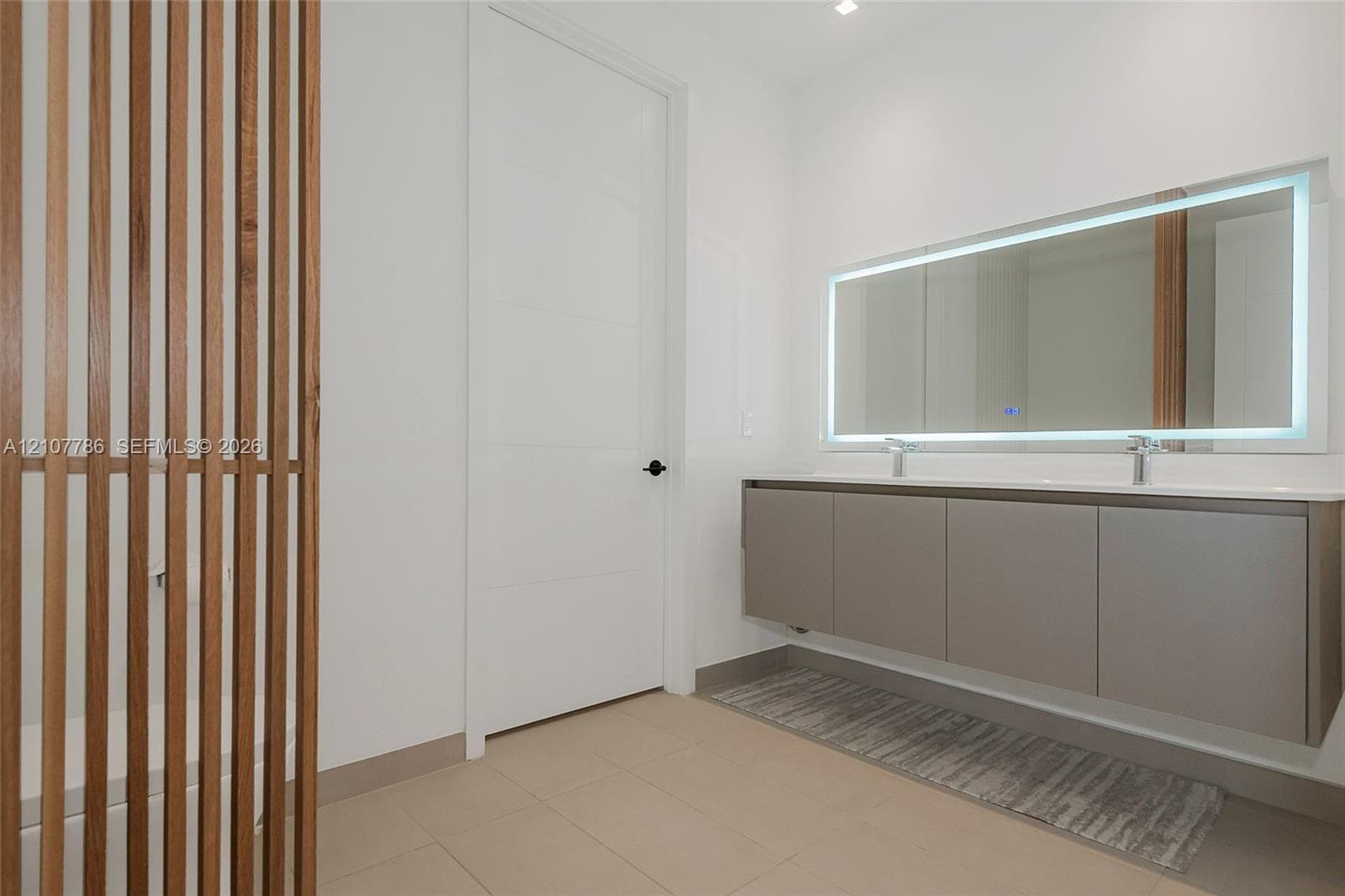 Floating double vanity with integrated sinks, back-lit mirror, and custom vertical wood slat screen
