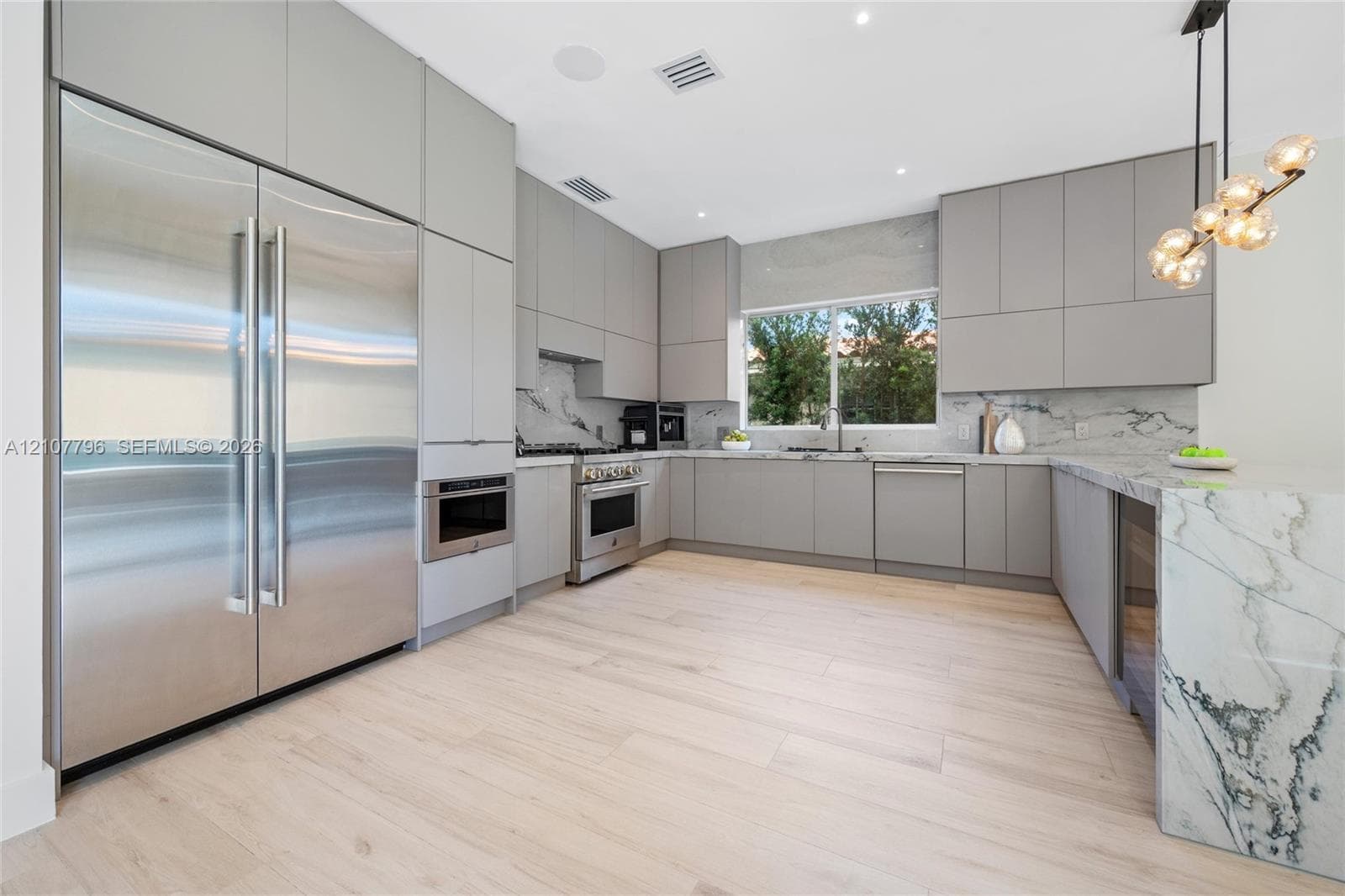 Kitchen featuring flat-panel cabinetry, stone slab countertops and backsplash, integrated stainless steel appliances, and wood-finish flooring