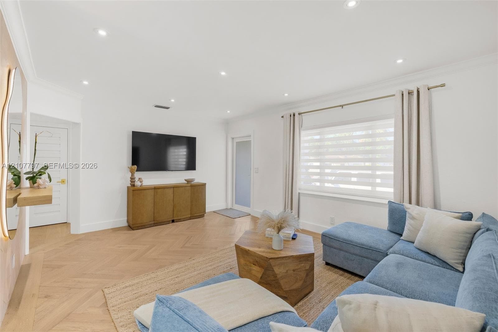 Herringbone-pattern wood-finish flooring, recessed lighting, crown molding, and a multi-lite exterior door with frosted glass paneling
