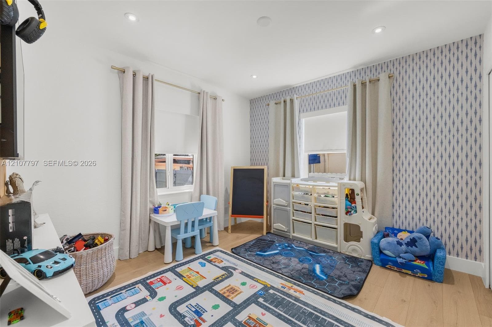 Room featuring wood-finish flooring, recessed lighting, and patterned accent wallpaper