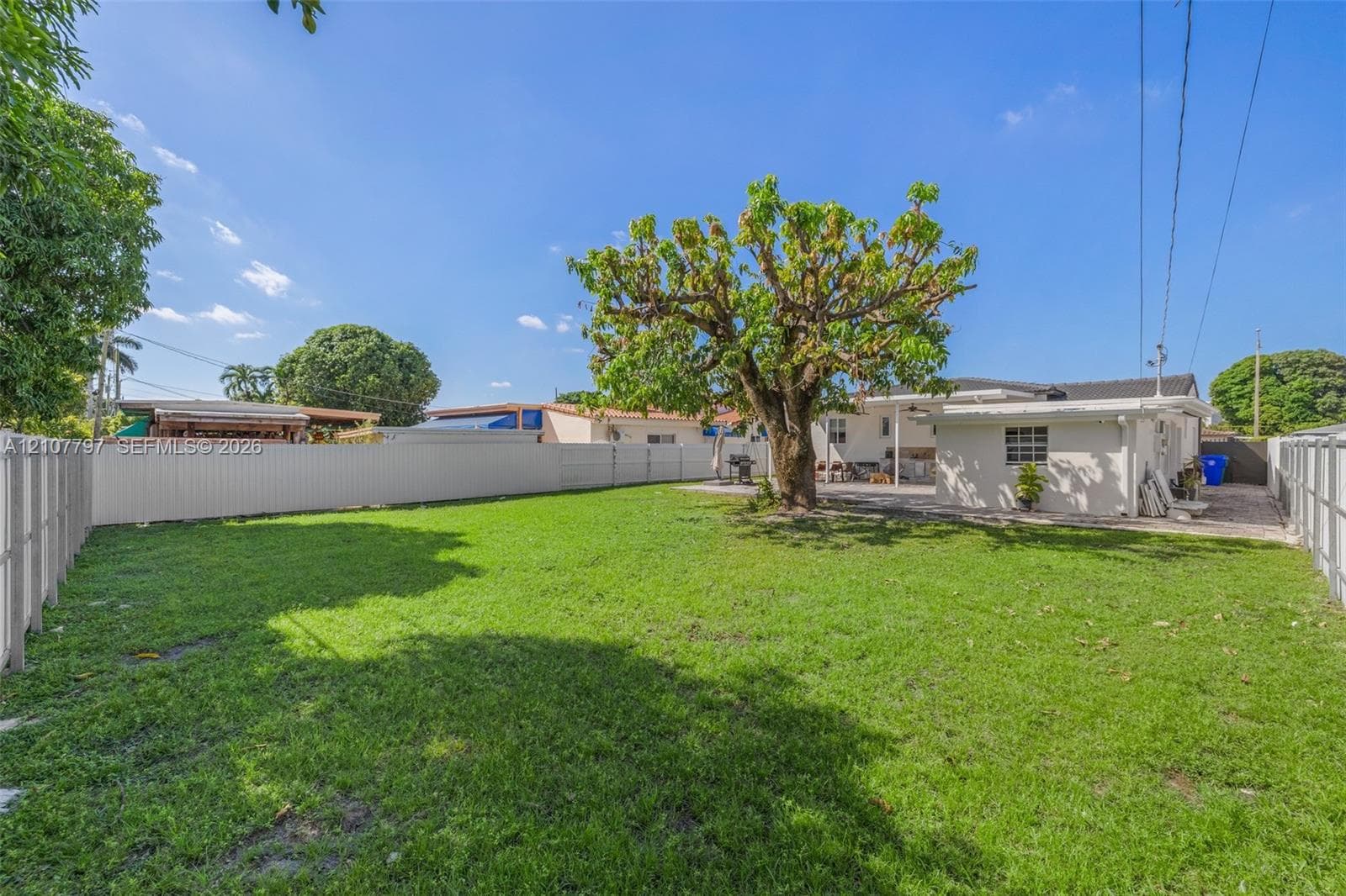 Single-story exterior featuring a paved driveway, full-perimeter metal fencing, dual-gate entry, and manicured landscaping